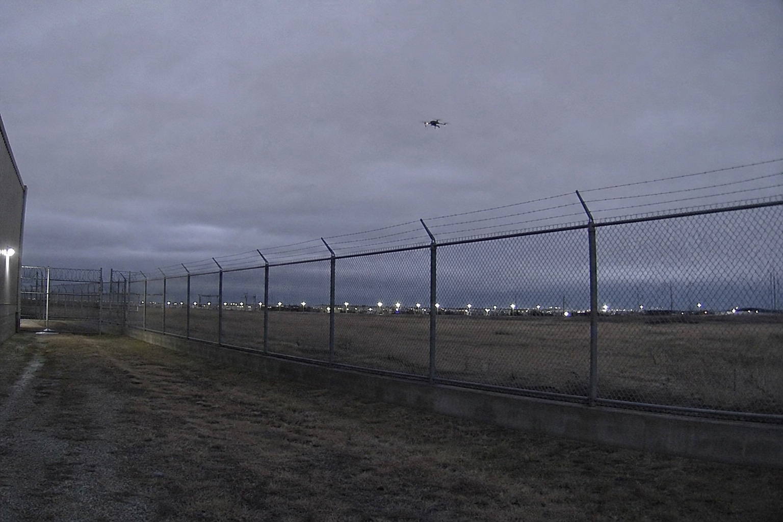 Small drone above a perimeter fence at dusk