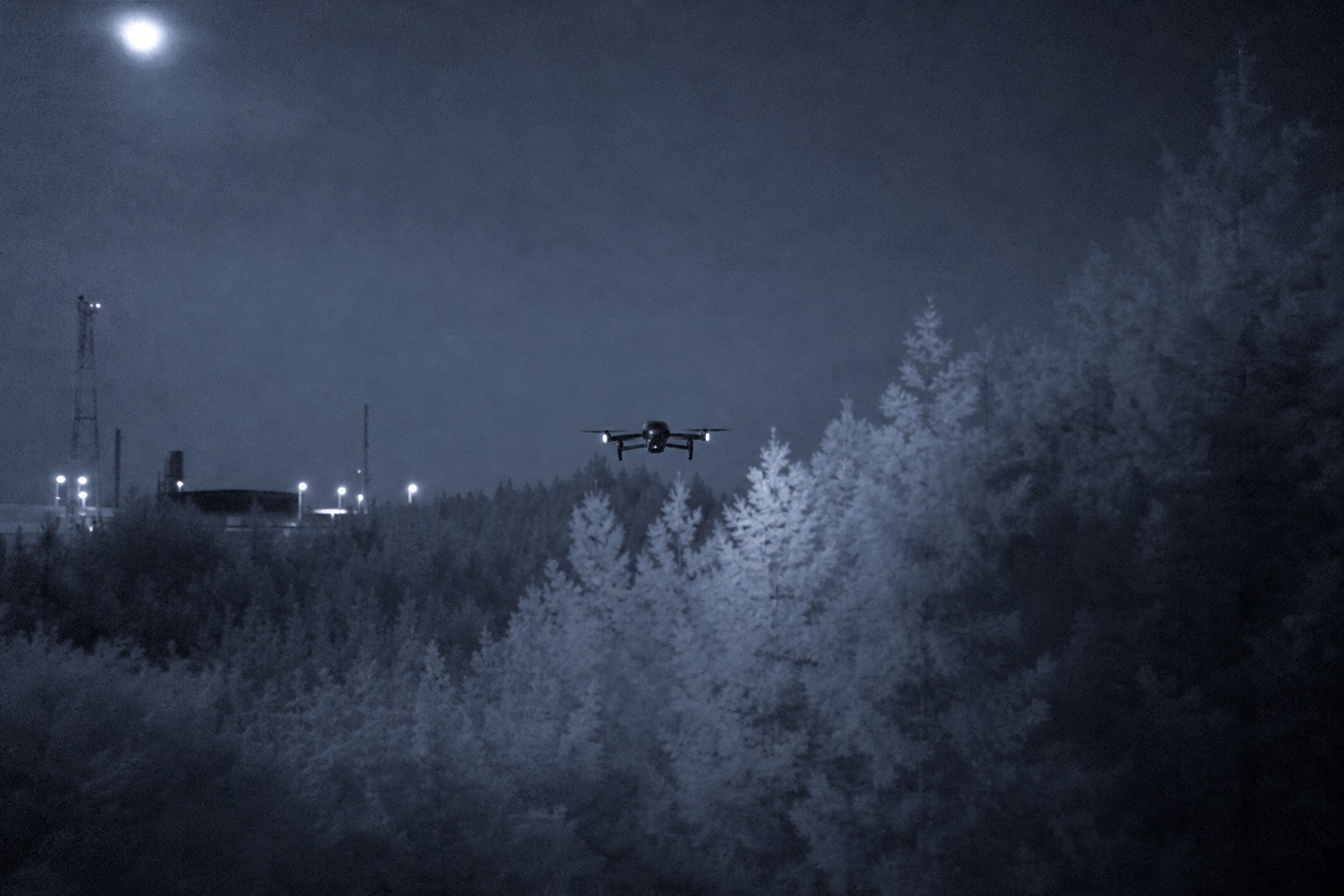 Drone silhouette over treeline at night